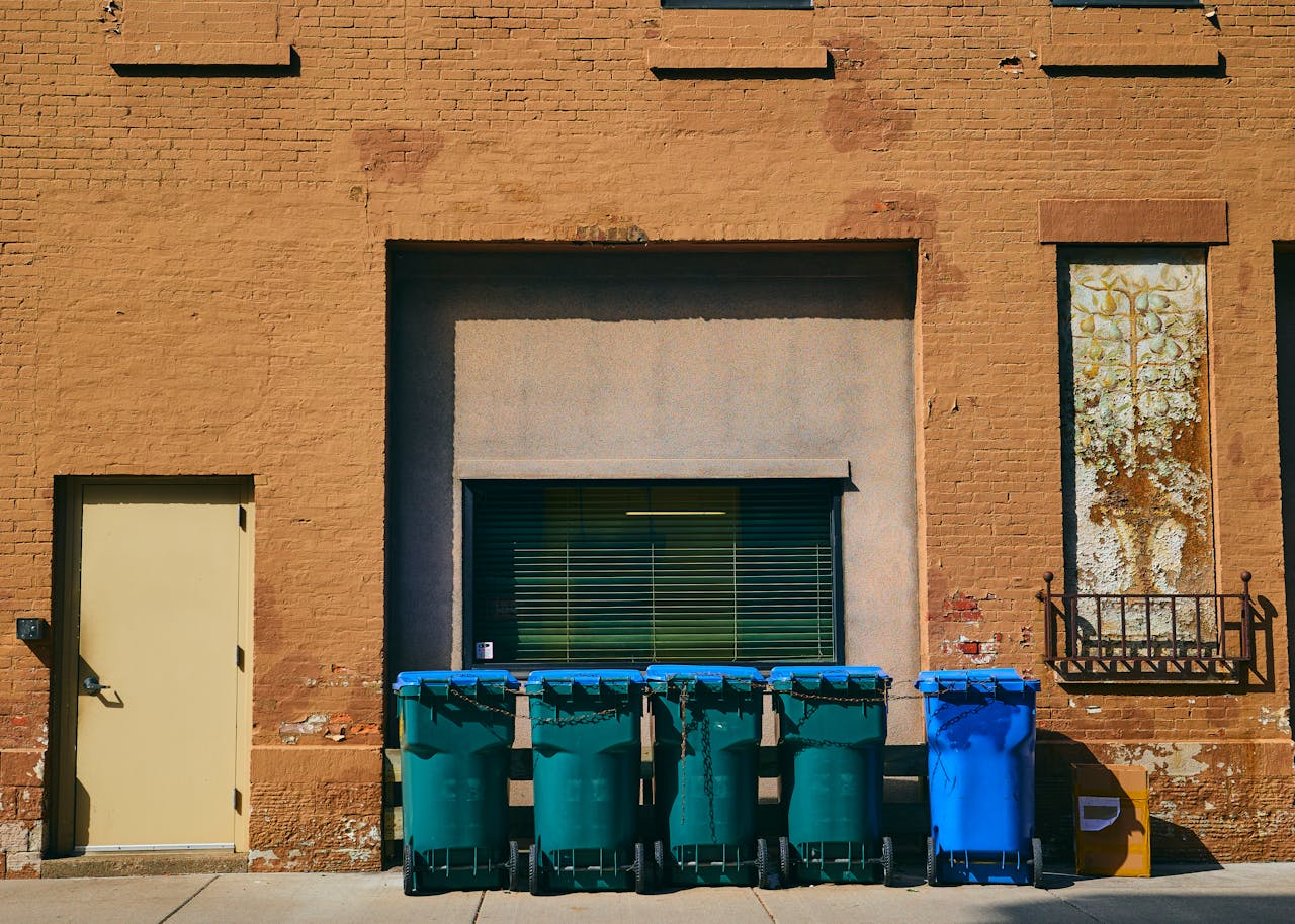 Grungy brick wall with trash bins in Rochester, NY, showcasing urban street aesthetics.
